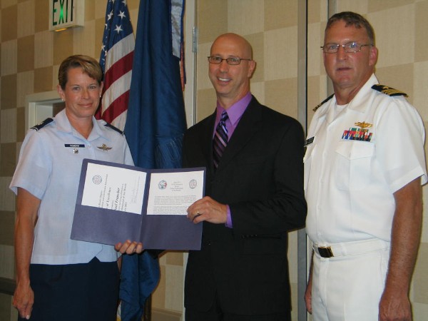 Cmdr. Vanderlip and Col. Romero present the July Civilian Cyber Professional of the Month Award to Michael Francher, Coalition C2 Interoperability Assessment team leader, U.S. Joint Staff.